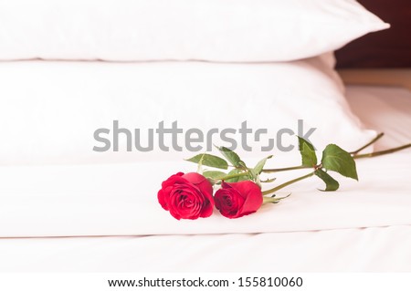 Romantic getaway with red roses on bed and fluffy pillows background