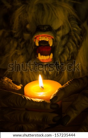 Werewolf head and the hands cradling a candle close up