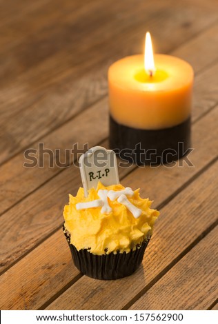 Halloween cupcake with tombstone cake topper and a two-tone candle close up