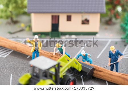 Miniature workers clearing a fallen tree after a storm top view
