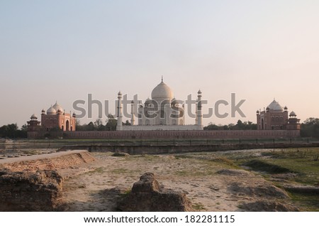 Taj Mahal, the white marble mausoleum with four minarets and two red sandstone buildings on either side of the mausoleum can be seen from across the Yamuna river during sunset close up