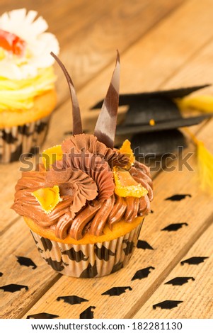 Graduation cupcakes with mortar board on wooden table close up