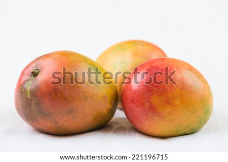 Red mangoes on a white stripes tablecloth background