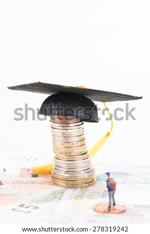 Miniature student looking at the mortarboard on top of a stack of coins close up