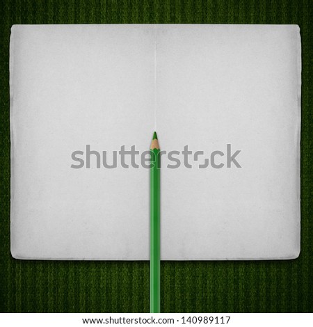 open notebook with green crayon on stripe pattern canvas background