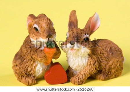 Two toy-rabbits with a heart. Yellow Background.
