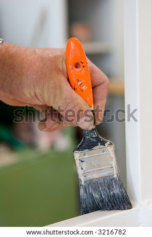 Craftsman restaurates a window with his paintbrush. Close-Up of Paintbrush and hand.