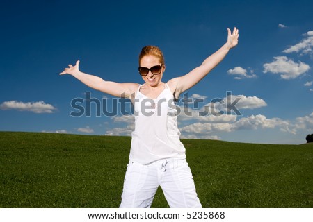 Woman on green meadow, happy and free. Grass going to the horizon, blue sky with clouds. Summery