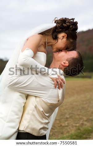 Groom lifted his bride - they want to kiss each other with a smile