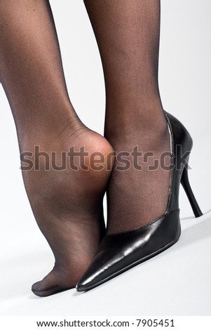stock photo Two female feet in black pantyhose and one black shoe
