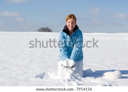 Nice woman kneeing in snow wanting to throw up a handful of snow