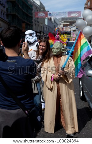 BRIGHTON, UK - AUG 13. LGBT participant in the Yoda costume from Star Wars movie taking photo with a tourist, in the pride parade at Brighton Pride Festival on August 13, 2011.