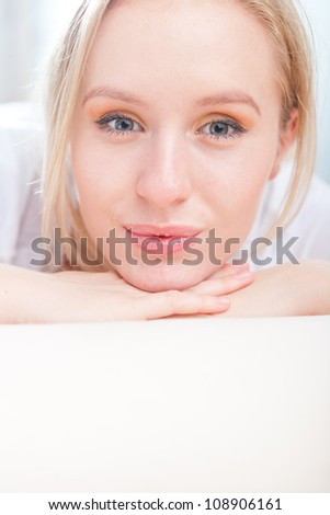 Closeup portrait of happy attractive young woman resting her head on her hand while relaxing on the floor