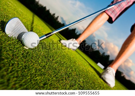 closeup shot of golf ball with golf club right before tee off, dynamically tilted picture