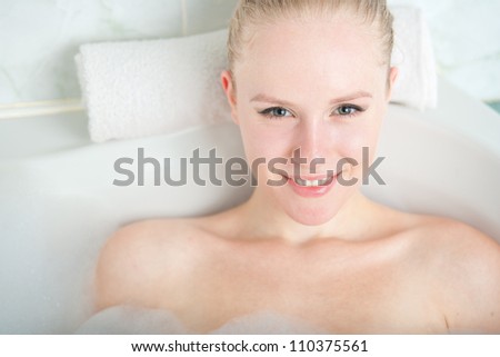 Bath woman enjoying bathub. Naturally beautiful female relaxing in bath with foam in bathroom