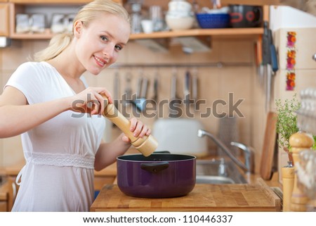 young woman cooking in the kitchen- adding salt and pepper into the pot, seasoning concept