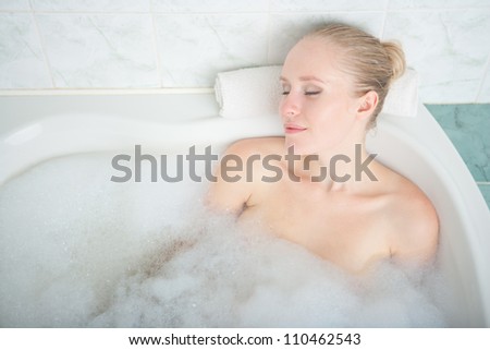 Bath woman enjoying bathtub. Naturally beautiful female relaxing in bath with foam in bathroom