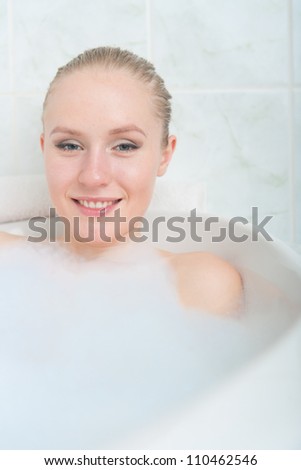 Bath woman enjoying bathtub. Naturally beautiful female relaxing in bath with foam in bathroom
