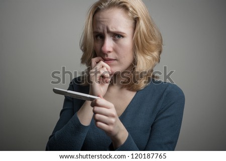 portrait of a sad young woman looking at pregnancy test with bad news