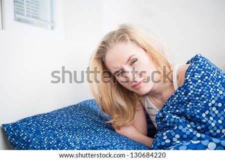 caucasian woman in bed, getting up late to work with terrible hangover, funny concept