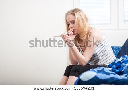 beautiful young woman in the bedroom worrying because of the pregnancy test result.