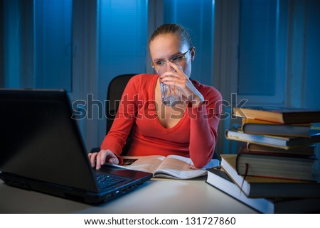 young  bored female college student studying poorly at late evening before exam, funny night procrastination concept