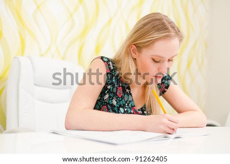 Beautiful young woman writing an exam and studying