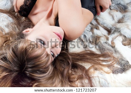 young and sexy beautiful woman with long hairs laying in the fur coat