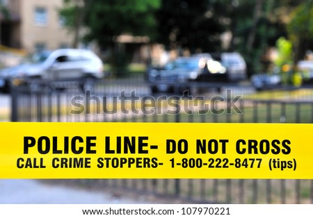 Police yellow  Ã¢Â?Â?POLICE LINE - Do not crossÃ¢Â?Â� tape (lower third) with fence and cars in the background
