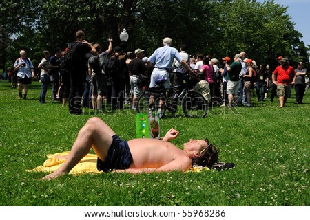 TORONTO-JUNE 25: Man sun-tanning in park while protesters gather at G20 Protest on June 25, 2010 in Toronto, Canada.