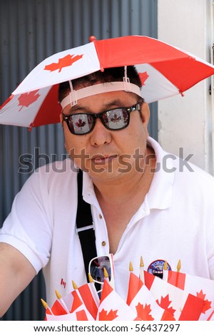 TORONTO - JULY 01: Man decorated with canadian flags, hat and sunglasses, enjoys the Canada Day parade in Toronto, July 01, 2010