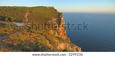 Wild red rocks of the cliff of Canaille cap and people and car in small - Cassis - Marseille - South of France - Panorama.