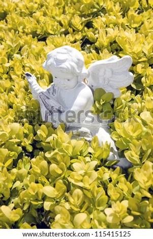 an angel statue playing music amongst garden flowers