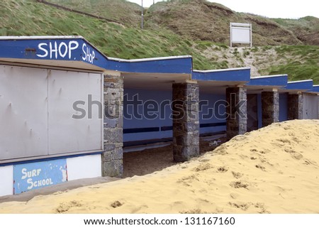 boarded up seaside shop front with sand blown all over the front