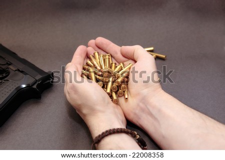 a stash of bullets in the hands and a gun  showing a dangerous cost to life against a dark background