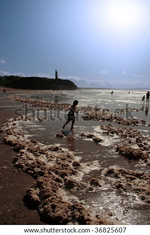 child paddling in the storm waves crashing in on ballybunion beach ireland