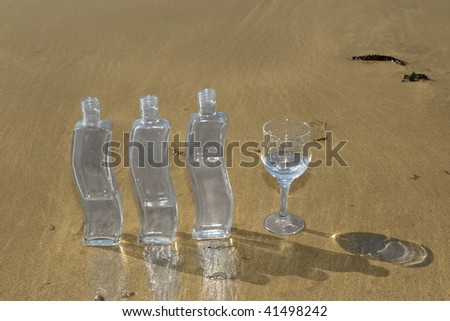 three bottles and a glass of pure natural water standing on the beach in kerry ireland