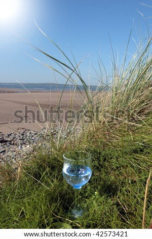 single glass of pure natural water standing on the beach dunes in kerry ireland