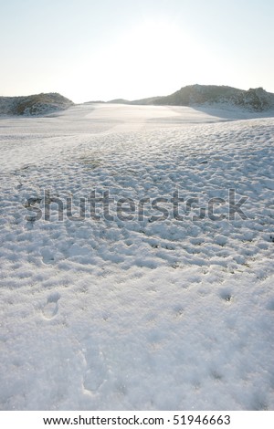 snow covered links golf course in ireland in winter with footprints