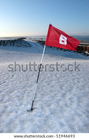 flag on a snow covered links golf course in ireland in winter