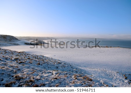 snow covered links golf course in ireland in winter with sea background