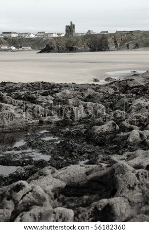 a rocky beach with castle on a warm day with a calm sea an ideal place to have a walk in ireland