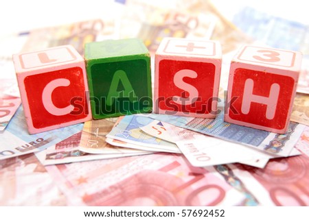 assorted childrens toy letter building blocks against a white background on money that spell cash
