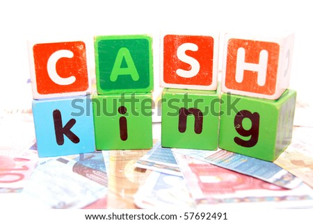 assorted childrens toy letter building blocks against a white background on money that spell cash king