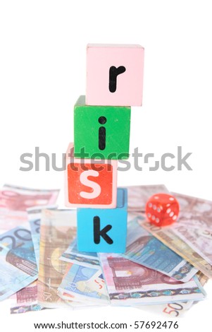 assorted childrens toy letter building blocks and dice against a white background on money that spell risk