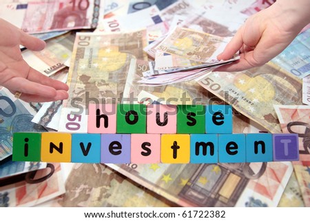 toy letters that spell house investment with cash in hands against a money background with clipping path