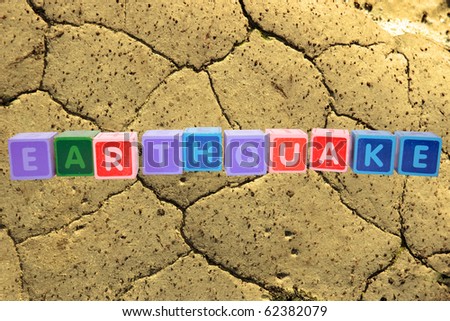 toy letters that spell earthquake against a barren land background with clipping path