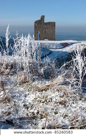 a seasonal snow covered view of atlantic ocean and ballybunion castle on a frosty snow covered winters day