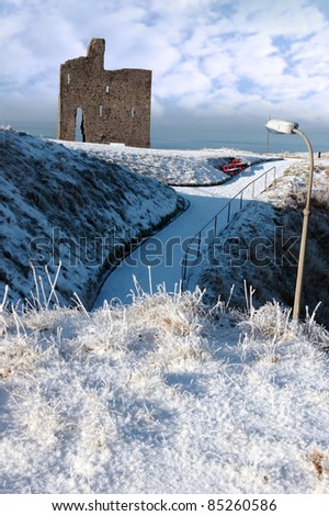 a seasonal snow covered view of atlantic ocean and ballybunion castle on a frosty snow covered winters day
