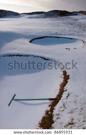 rakes in bunkers on a snow covered links golf course in ireland in snowy winter weather
